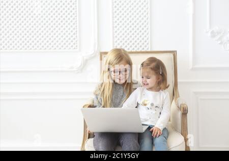 Zwei liebenswerte kleine Schwestern, die ihren Computer-Laptop zusammen benutzen Stockfoto