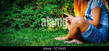 E-Learning im Park. Studentin studing mit Tablet-PC, während sie auf dem Gras sitzen gekreuzt. Seitenansicht. Viel Copyspace Stockfoto