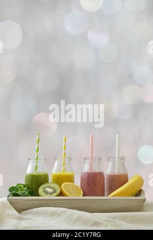 Bunte Frucht-Smoothies in einer Reihe mit frischen Früchten Stockfoto