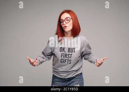 Swag und zuversichtlich rothaarigen Mädchen in Jeans und Sweatshirt bei Grey studio posieren. Stockfoto