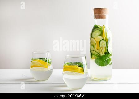 Freche Diät Wasser. Gurke, Zitrone, Minzlimonade in Gläsern auf weißem Holztisch. Stockfoto