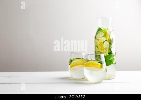 Freche Diät Wasser. Gurke, Zitrone, Minzlimonade in Gläsern auf weißem Holztisch. Stockfoto