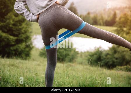 Nahaufnahme Bild von Beinen, macht Kraftübungen mit Widerstand Fitness Gummiband. Gesundes Lifestyle-Konzept. Sommersaison Stockfoto
