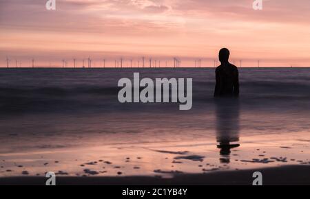 Silhouette einer Iron man Skulptur bei Sonnenuntergang am Strand bei Liverpool, England im Juni 2020. Stockfoto