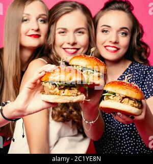 Hübsche Freundinnen mit saftigen Hamburger. Stockfoto