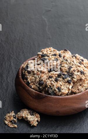 Protein-Granola-Cracker mit Rosinen und Nüssen auf schwarzem Stein Hintergrund Stockfoto