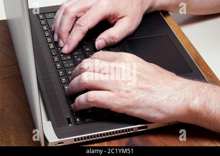 Männliche Hände tippen auf einem Laptop Computer keybord. Business, studyng, intelligente Arbeitskonzepte Stockfoto
