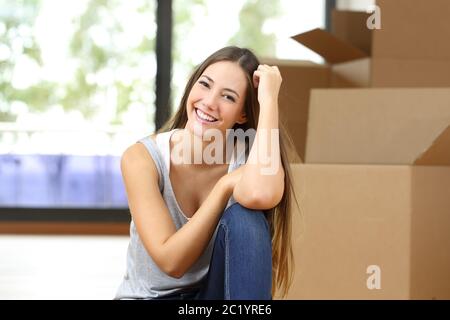 Glückliche Frau Umzug nach Hause posiert Blick auf Kamera sitzen auf dem Boden mit Boxen Stockfoto