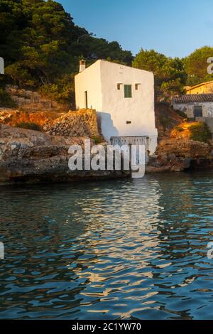 Schöne Aussicht Felsen Bucht Strand traditionelles Haus Dorf, Cala S'Almunia, Mallorca Insel, Spanien. Private Villen über ruhigen azurblauen Meer während Sonnenaufgang Stockfoto