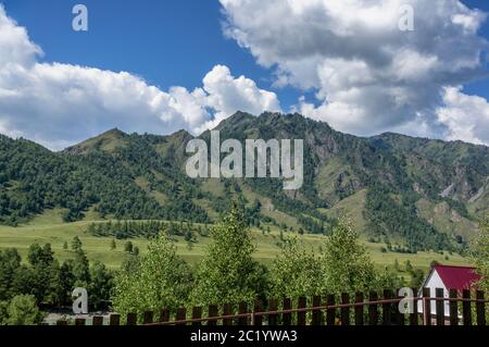 Kleine Häuser zwischen grünen Bergen und Himmel mit blauen Wolken Stockfoto