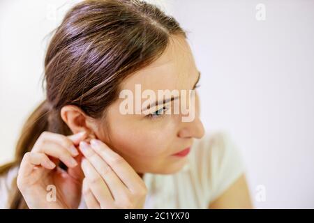 Frau, die Ohrringe an ihre Ohren setzt Stockfoto