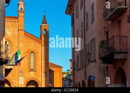 Blick auf die Kathedrale von San Lorenzo unter alten Häusern unter blauem Himmel in Alba, Piemont, Norditalien. Stockfoto