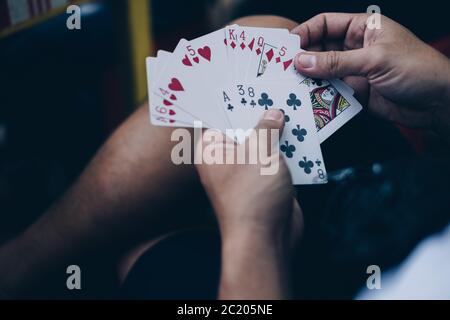 Hände die ausgeteilten Spielkarten in einem Pokerspiel ordnen. Selektiver Fokus. Stockfoto
