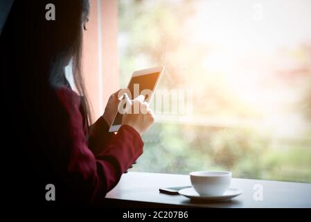 Porträt der jungen asiatischen Geschäftsfrau sitzt drinnen im Café mit digitalen Tablet mit Kaffee. Business Success Concept. Stockfoto