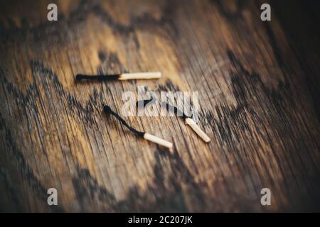 Drei ausgebrannte dünne Streichhölzer liegen auf einem alten Holztisch. Einer von ihnen brach. Tod. Stockfoto
