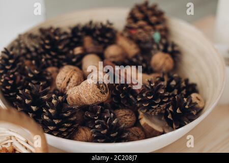 Nahaufnahme von Lärchenzapfen zur Dekoration, einige gefallene kleine Kegel eines Lärchenbaums, der auf einer Holzplatte als Hintergrund liegt Stockfoto