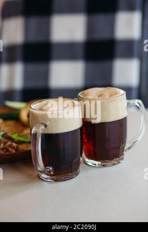 Zwei große Glas Tassen voll mit schäumendem Bier. Stockfoto