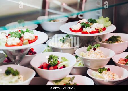 Viele runde Teller mit leckeren Gemüse Schüssel Salat im Restaurant. Stockfoto