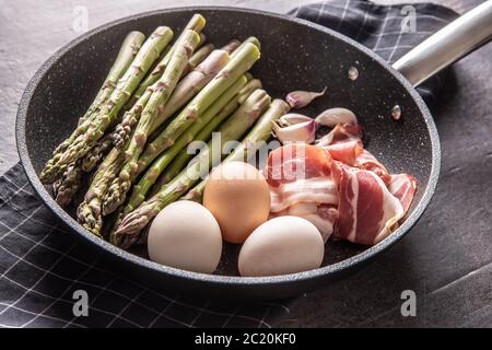 Spargel Eier Speck und Knoblauch in Keramikpfanne Stockfoto