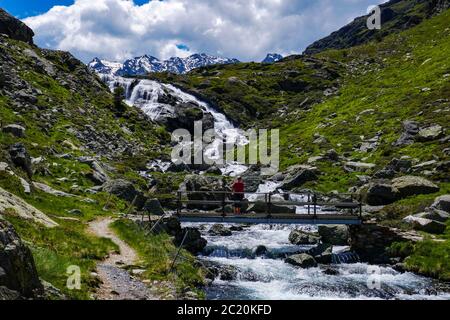 Einsame weibliche Wanderer mit Bach mit Kaskaden fließt durch das Soulcem Tal in den französischen Pyrenäen, Ariege Region, Frankreich, Pyrenäen Berge Stockfoto