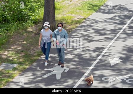 Ein asiatisch-amerikanisches Paar, wahrscheinlich Koreaner, führt mit ihrem Hund einen Spaziergang auf einem Pfad in der Nähe der Bayside Marina in Queens, New York City. Stockfoto