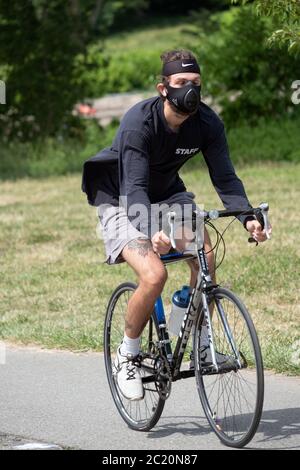 Ein junger Mann, der wahrscheinlich in den 30er Jahren auf dem Radweg in Little Bay Park unterwegs war, während er eine OP-Maske trug. In Whitestone, Queens, NYC. Stockfoto