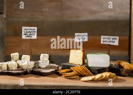 Rustikale Käseplatte mit einer Auswahl an etikettierten Käsesorten und Räucherfleisch mit Trauben. Stockfoto