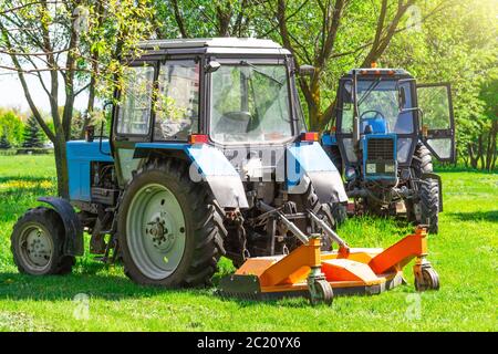 Traktor verwendet gezogene Rasenmäher, um Gras auf städtischen Rasen mähen Stockfoto