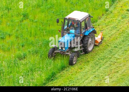 Traktor verwendet gezogene Rasenmäher, um Gras auf Stadtrasen zu mähen, Luftaufnahme Stockfoto