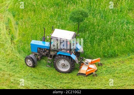 Traktor verwendet gezogene Rasenmäher, um Gras auf Stadtrasen zu mähen, Luftaufnahme Stockfoto