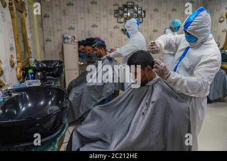 Dhaka, Bangladesch. Juni 2020. Barbiere in Schutzanzügen und Gesichtsmasken bieten dem Kunden während der COVID-19-Coronavirus-Pandemie in Dhaka, Bangladesch, einen Haarschnitt-Service in einem Salon. Kredit: Zabed Hasnain Chowdhury/ZUMA Wire/Alamy Live Nachrichten Stockfoto