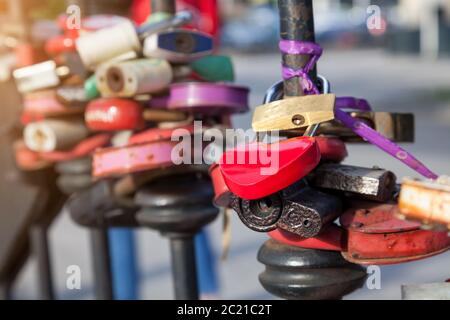 Metallzaun an der Stadtpromenade mit Vorhängeschlössern in verschiedenen Formen und Farben: Rosa, alte Scheunenherzen, mit verbundenen Bändern, von den frisch vermählten Vermählten geschlossen Stockfoto