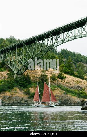 Ein Segelboot unter der Deception Pass Bridge in Anacortes, Washington Stockfoto