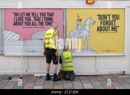 Glasgow, Schottland, Großbritannien. Juni 2020. Zwei Mitglieder von Jack Arts Scotland, die Poster mit Wahrzeichen von Glasgow und Liedtexten fixieren. Ein Poster zeigt eine Zeichnung von The Armadillo und The SSE Hydro mit den Worten Oh Let Me Tell You That I Love You...That I Think About You All The Time, die Texte aus Kaledonien von Dougie MacLean sind. Das andere Poster zeigt eine Zeichnung der Duke of Wellington Statue mit den Worten Don't You Forget About Me, die Texte aus dem gleichnamigen Song von Simple Minds sind. Beide Poster sagen, halten Sie Ausschau nach einander Glasgow. Kredit: Skully/Alamy Live Nachrichten Stockfoto