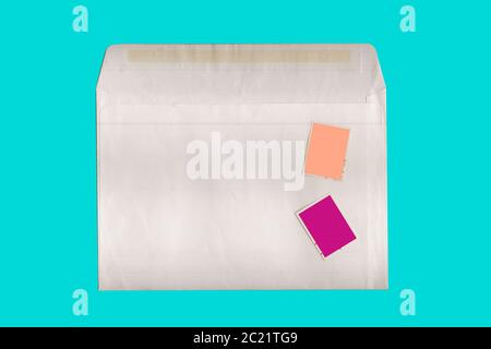 Umschlag mit zwei Briefmarken öffnen. Leerer Umschlag, Rückseite. Isolieren Sie auf einem türkisfarbenen Hintergrund. Blick von oben. Stockfoto