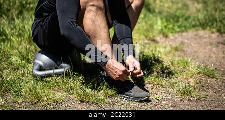 Junge Sportler auf Sport Schuhe Schnürsenkel binden. Fit, Fitness, Bewegung, Training und gesunde Lebensweise. Stockfoto