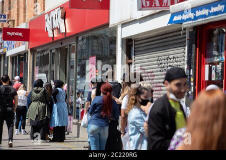 Kilburn High Road, London, England nicht-wesentliche Geschäfte öffnen sich nach der erzwungenen Schließung im März 2020 aufgrund von Covid-19 wieder, Kunden warten auf TK Max Stockfoto