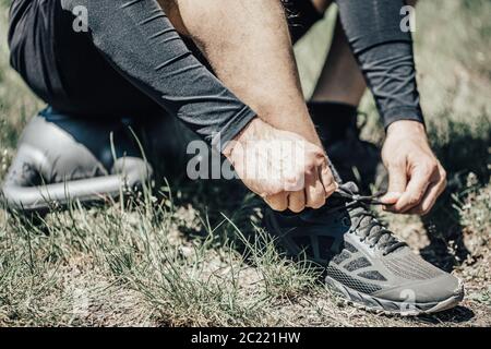 Nahaufnahme eines attraktiven jungen Mannes, der Schnürsenkel bindet, bevor er im Freien läuft Stockfoto