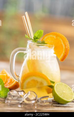 Erfrischendes Glas Orangenlimonade mit Eis, Minze und Papierhalmen Stockfoto