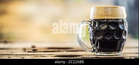 Ein Pint dunkles Bier auf einem Holztisch, der auf der Seite eines Fotos steht Stockfoto