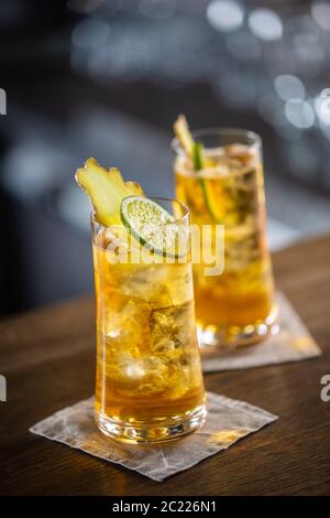 Zwei Gläser Whisky und Ingwer-Limonade mit Eis und Scheiben von frischem Ingwer und Limette Stockfoto