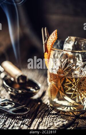 Whisky ohne Eis in einer Tasse mit brennender Zigarre und einem alten Holzfass im Hintergrund Stockfoto