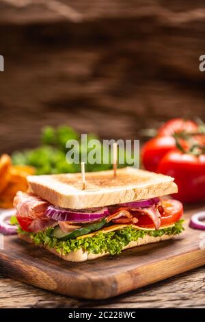 BLT Sandwich mit Zwiebel auf einem Schneidebrett mit dunklem Hintergrund Stockfoto