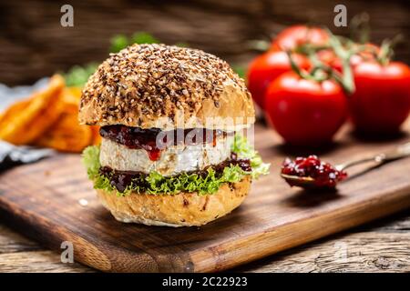 Vegetarischer Burger mit Camembert und Cranberry-Sauce auf rustikalem Holzbrett Stockfoto