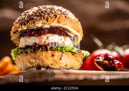 Vegetarischer Burger mit Camembert und Cranberry-Sauce auf rustikalem Holzbrett Stockfoto