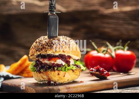 Vegetarischer Burger mit Camembert und Cranberry-Sauce auf rustikalem Holzbrett Stockfoto