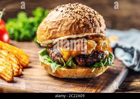 Rinderburger mit karamellisierten Zwiebeln, Rucola und geschmolzenem Käse Stockfoto