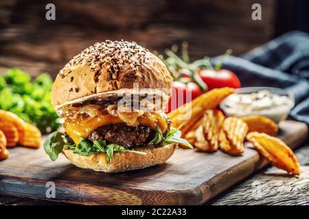 Hamburger mit karamellisierter Zwiebel, Rucola und geschmolzenem Käse Stockfoto