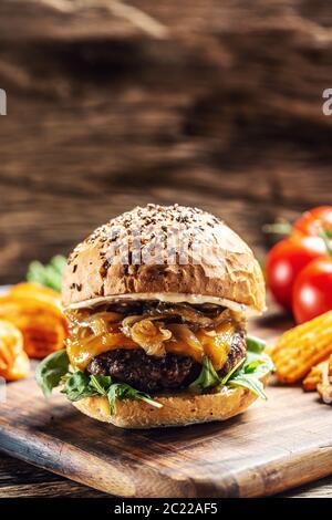 Rinderburger mit karamellisierten Zwiebeln, Rucola und geschmolzenem Käse Stockfoto