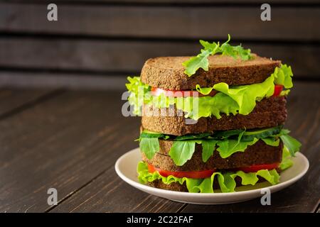 Sandwiches mit Salat und Rucola, Tomaten und Gurken, vegane Sandwiches aus grobem dunklem Brot mit frischem Gemüse Stockfoto